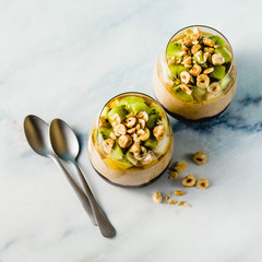 Vegan layered banana dessert of green buckwheat, chia seeds and quinoa with blueberry jam in a glass with fresh fruits, nuts and honey. healthy morning meal for breakfast.
