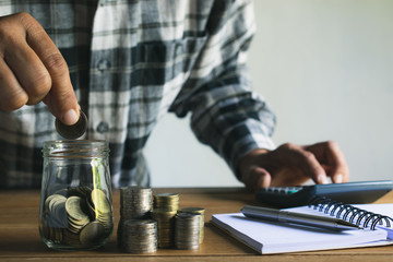 Business man putting coin in glass bottle saving bank and account for his money all in finance accounting concept.