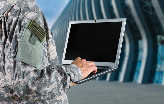 Young military soldier man portrait with laptop on  background