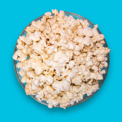 Popcorn in a transparent plate on a blue background.