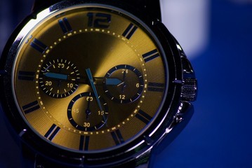 A gold watch  with a blue background