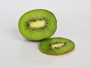 Half fruit and green slice of kiwi on a white glossy background with water drops, healthy eating...