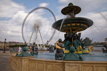 Fototapeta na wymiar Paris, France - May 16, 2018: Fountain in the Place de la Concorde in Paris, France, with rotating ferris wheel in the background