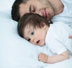 father and baby sleeping peacefully in bed