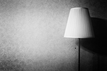 Black and white foto of an floor lamp on the background of a concrete wall