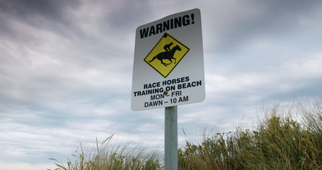 Low angle of warning sign advertising race horses training at Port Fairy, Australia.