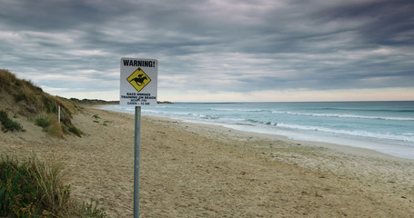 Wide shot of warning sign advertising race horses training on Golfies Beach, Port Fairy, Australia.