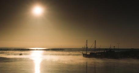 Fishing boats silhouetted against misty sunrise at Fisherman's Wharf, Portland.