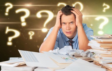 Tired young businessman with many business papers