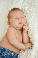 Fashionable newborn baby in jeans sleeping in bed. Fashion for children.