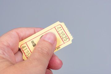 Hand holding a yellow raffle ticket isolated on gray with copy space