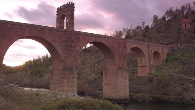 Cinematic tracking shot of Alc&radic;&deg;ntara Bridge at golden hour