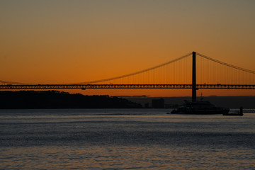 Fototapeta na wymiar Sunset view of Tagus river (Rio Tajo) and 25th of April Bridge (Ponte 25 de Abril). Lisbon, Portugal