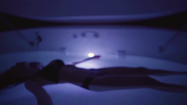 Young Woman in float tank, sensory depravation tank at spa