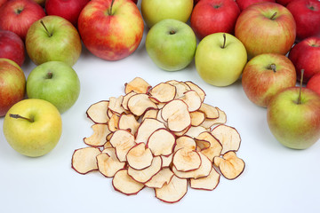 Dried Apple slices surrounded by fresh apples on white background