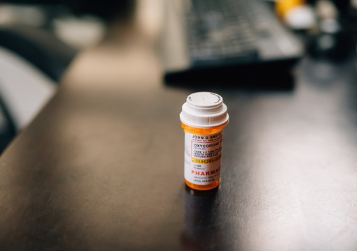 african american man taking opioid pills sitting at a dark table - Powered by Adobe