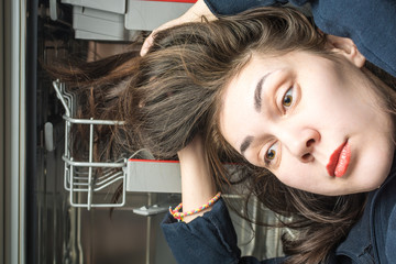 Girl lays long greasy hair in the dishwasher compartment