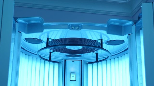 Vertical solarium cabin with blue working lamps