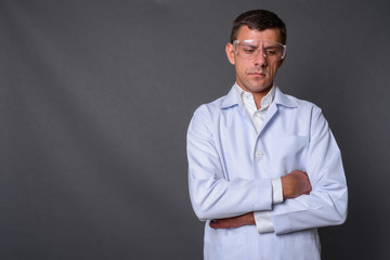 Handsome man doctor wearing protective glasses against gray back