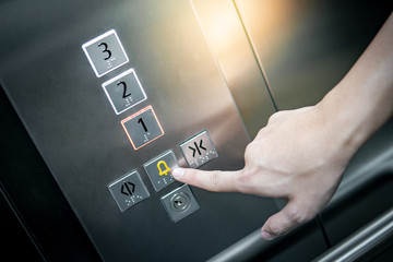 Male forefinger pressing on emergency stop and alarm button in elevator (lift). Mechanical...