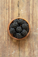 Blackberries in a wood bowl on a farm table.
