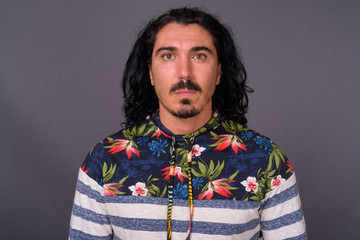 Handsome man with curly hair and mustache against gray backgroun