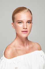 Portrait of a graceful blonde with a smooth hairstyle. Light tone, high key. Highlighter in make-up.
