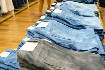 Stack of blue and black jeans in clothes shop.