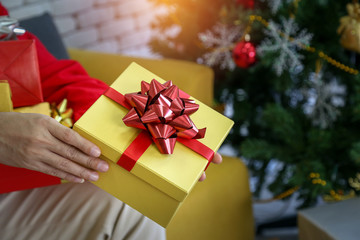 Close up to the man hands giving gift box with red bow for merry christmas and happy new year, holiday event.