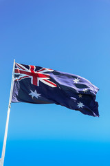 Flag of Australia flying high against a sunny clear sky