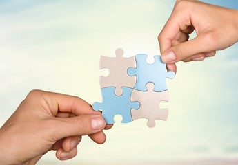 Human hands joining puzzle parts on background