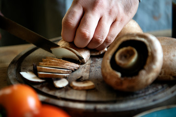 Man slicing portobello mushrooms - obrazy, fototapety, plakaty