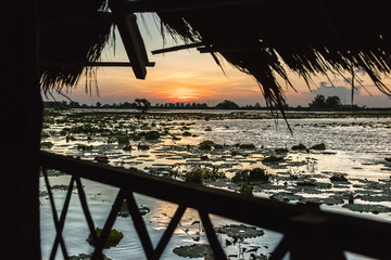 magical sunset with reflections in the lake with traditional straw huts