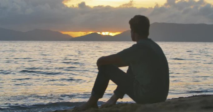 Young Man Sits on the Beach and Watches the Sunset, Tropical Ocean, Australia