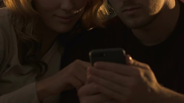 Closeup of couple using smartphone together, ordering food online for dinner
