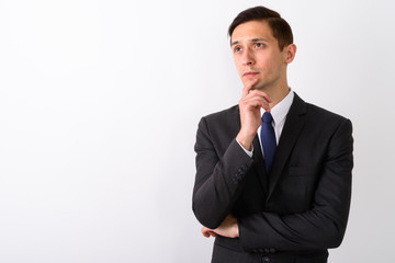 Studio shot of young handsome businessman thinking while looking