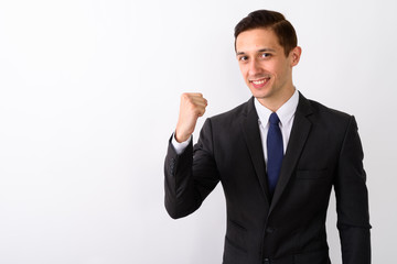 Studio shot of young happy businessman smiling while looking mot