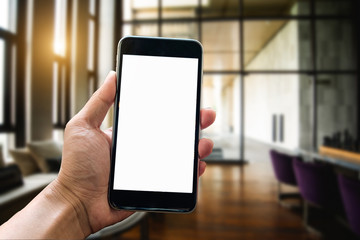 A man hand holding smart phone device in the bright office room interior.