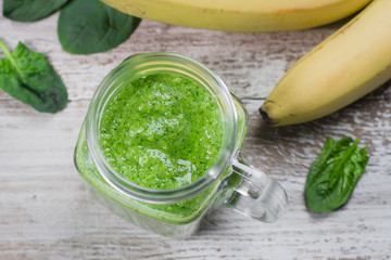 Detox concept. Spinach smoothie in mason jar. Healthy Raw Vegetarian Smoothie on wooden table. Top view, flat lay