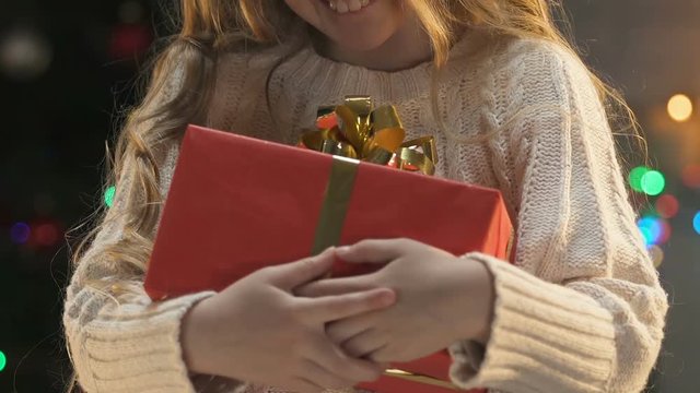 Happy girl holding Christmas gift, concept of orphanage volunteering at holidays