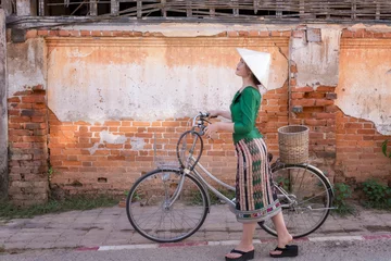 Fotobehang Young woman wearing Laos traditional dress with bicycle walking tourism in walking street Chiang Khan Loei Thailand. © EmmaStock