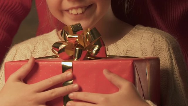 Parent giving gift to happy daughter, merry Christmas in childhood, closeup