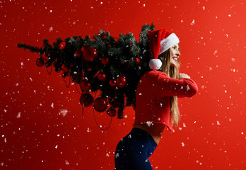 sexy Christmas fitness sport woman wearing santa hat holding xmas tree on her shoulders. snowflakes
