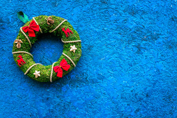 Christmas wreath traditional, classic type. Wreath made of spruce branches and red ribbons on blue background top view space for text