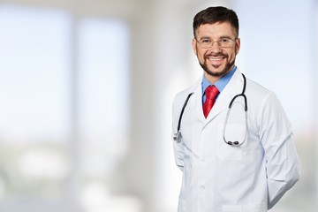 Handsome young male doctor with blurred hospital interior on