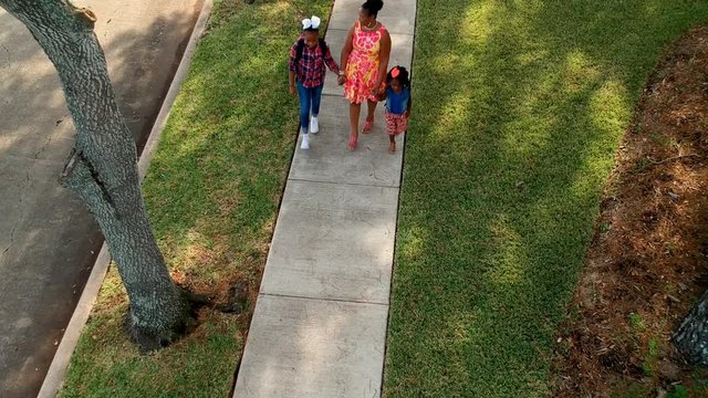 A mom home from work just in time to walk with the kids after school. Drone, aerial footage