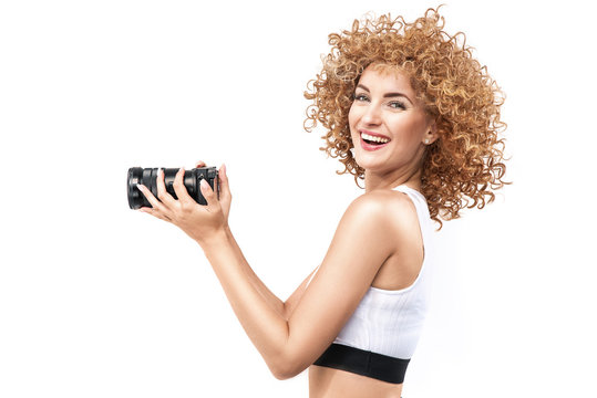 Commercial style portrait of a ginger, frizzy-haired woman holding a camera