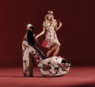 Conceptual portrait of a young hippe standing on the giant, flowered shoe