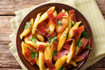 German potato schupfnudeln with ham and herbs close-up on a plate. horizontal top view