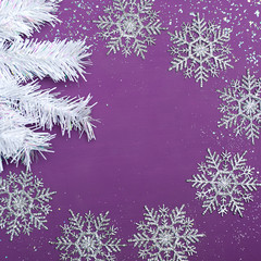 Fototapeta na wymiar Christmas background with free space. Textural wooden background of bright purple color with white artificial fir branches, artificial snow, sparkles, Christmas balls 